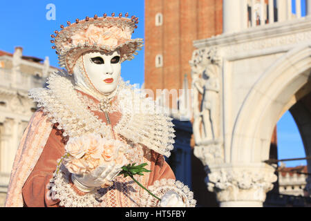 A lady in a traditional Venetian dress decorated with roses outside the Doge's Palace during the Carnival of Venice, Italy Stock Photo