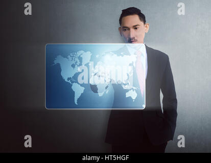 Modern asian businessman touching virtual world map on digital screen over wall background Stock Photo