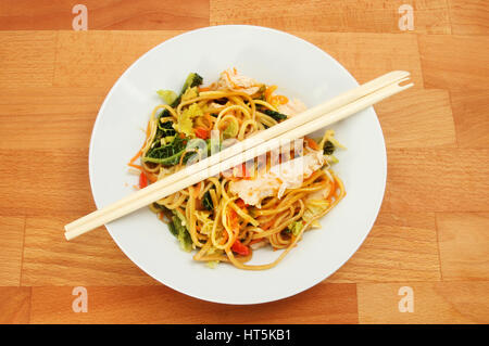 Chicken Chow Mein in a bowl with chopsticks on a wooden tabletop Stock Photo