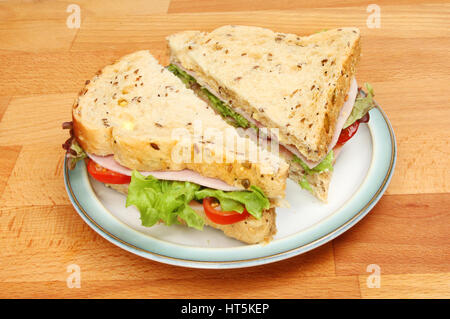 Fresh ham salad sandwich made with seeded bread on a plate on a wooden tabletop Stock Photo