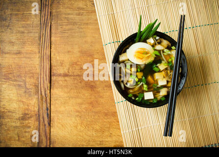 Japanese miso soup in black cup on bamboo mat background Stock Photo