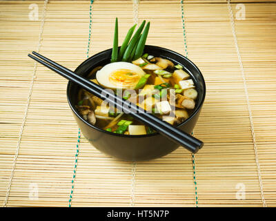Japanese miso soup in black bowl on bamboo mat Stock Photo