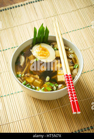Miso soup in white bowl on bamboo mat