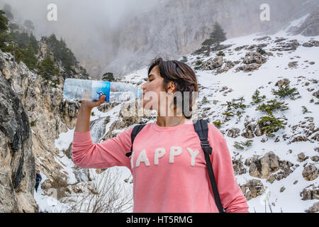 thirsty girl drinking water in winter on snow mountain Stock Photo