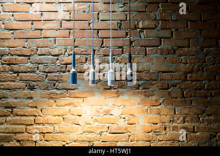 Glowing hanging multi-colored lamps in a loft style on the brick wall background. Closeup. Horizontal. Stock Photo