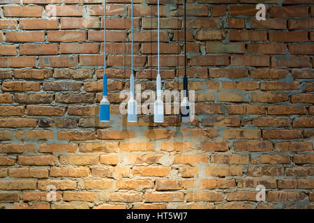 Luminous hanging multi-colored lamps in a loft style on the brick wall background. Closeup. Horizontal. Stock Photo