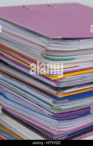 Several multicolored folders with documents stacked in a pile on the table. Close-up Stock Photo