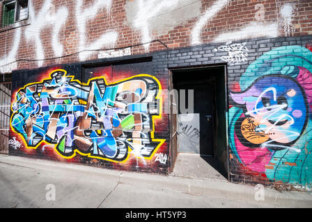 A graffiti covered wall and doorway on a building in a back alley of Kensington Market in Toronto Ontario Canada. Stock Photo