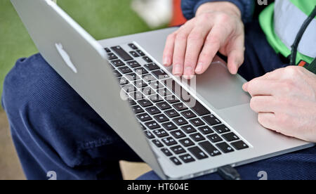 Photographer using an Apple MacBook Pro laptop computer to send images from side of football pitch Stock Photo