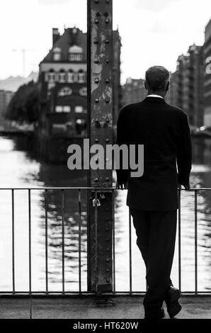 Lonely business man in black suite turned backwards, in the old city of hamburg, germany. Thinking of new strategy. Stock Photo