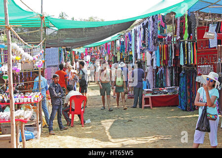 Shops, vendors and customers at the Wednesday flea market of varieties of trendy and fashinalble merchandise in Anjuna Beach, Goa, India Stock Photo