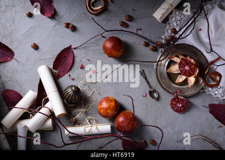 Overhead view of red oranges on a table with leaves and paper scrolls. Romantic love letter or wedding invitations. Top view Stock Photo