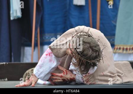 Jesus Christ falls on the way to his crucifixion, during the street performances Mystery of the Passion. Stock Photo