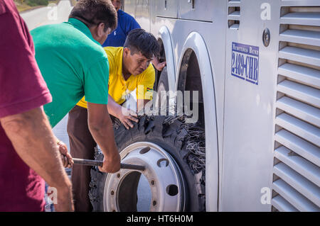 Puerto Suarez, Bolivia on August 21, 2015: Mechanic changing flat tire at bus breakdown Stock Photo