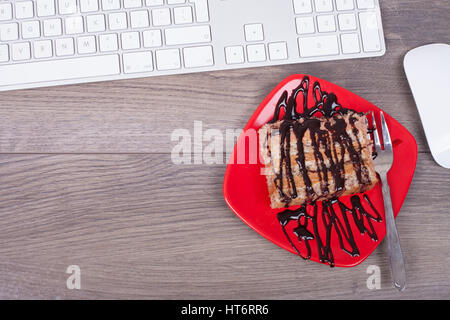 Keyboard  and dessert in a plate on a wooden table from above Stock Photo