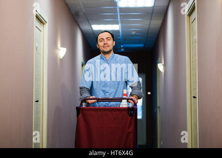 Young handsome pushing cleaning cart - a series of HOTEL images. Stock Photo