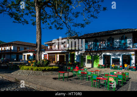 Colombian peasants sit in a coffee-shop in front of the colonial houses at the main plaza of Jardín, a village in the coffee region of Colombia. Stock Photo