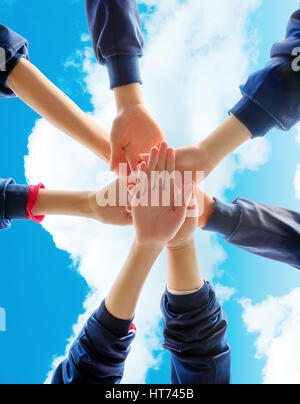 Group of young people putting their hands on top of each other. Close up image of young students making a stack of hands. Stock Photo