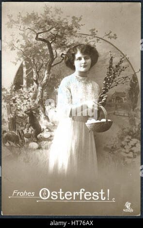 A postcard printed in Germany, shows a rural landscape, a girl with a basket of eggs and sprigs of willow. The inscription in German: Happy Easter Stock Photo
