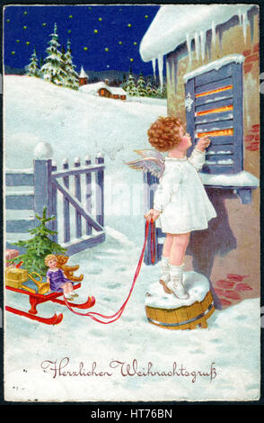 A Christamas postcard printed in Germany, shows a little girl in the image of an angel with gifts. The inscription in German: Merry Christmas Stock Photo