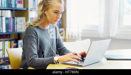 Hardworking female student working on laptop in the library Stock Photo