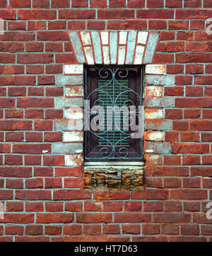 Window in brick wall. Skillful framing of window hole. Wrought iron grille curly Stock Photo
