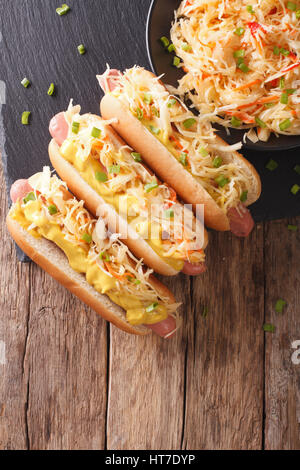Hot dog with sauerkraut and mustard close up on the table. Vertical view from above Stock Photo