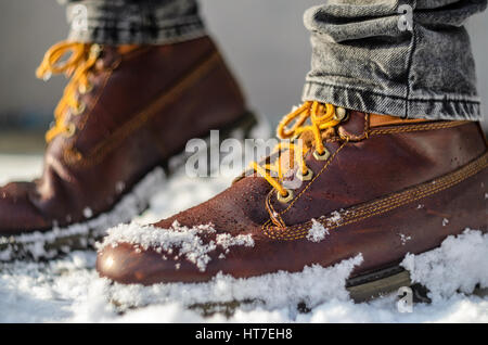Brown leather shoes in the snow. Shoe Detail. Shallow depth of field. Legs in the warmth concept Stock Photo