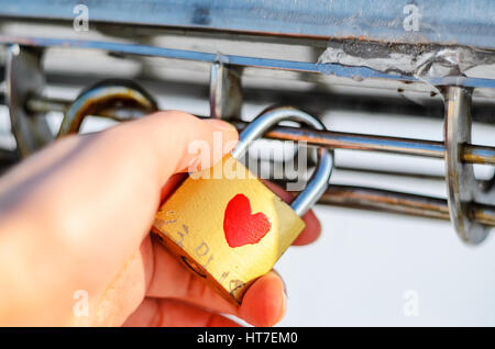 Old padlock with heart pattern on the palm. Checking the strength of the concept Stock Photo