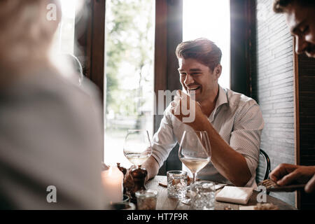 Indoor shot of young man smiling with friends at restaurant. Young people meeting at a cafe. Stock Photo