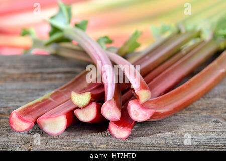 Fresh rhubarb on a wooden table, in the background other rhubarb stalks in soft focus Stock Photo