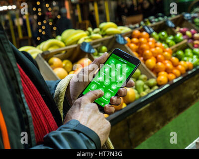 Man holding iPhone 7plus smartphone using detox app for suggestions for  a detoxing produce diet in Borough Market Southwark London UK Stock Photo