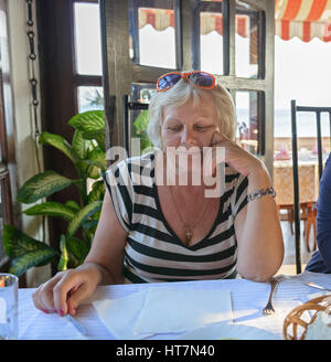 Aged woman is waiting for dinner dishes in resort cafe. Stock Photo