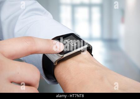Businessman checking time on modern smart watch. Office in background Stock Photo
