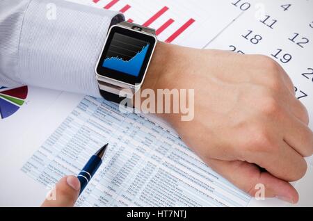 Man working with smart watch in office. Chart on screen Stock Photo