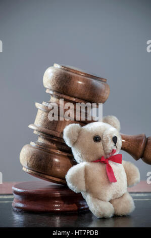 Judges Gavel child custody divorce abuse trust legal concept on desk with child's small Teddy Bear leaning against in law court environment Stock Photo