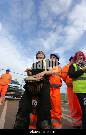 Fylde, Lancashire, UK. 8th Mar, 2017. An anti fracking protester banging a drum stood in front of security guards at the Caudrilla site on Preston New Road, Fylde, Lancashire, 8th March, 2017 Credit: Barbara Cook/Alamy Live News Stock Photo