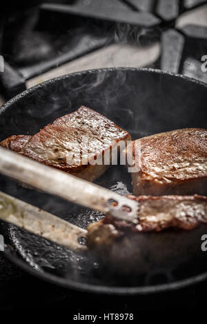 Pork meat steak fried in pan in restaurant kitchen Stock Photo