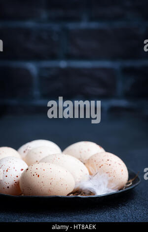 raw chicken eggs on plate and on a table Stock Photo