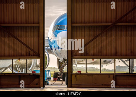 Blue airplane in front of half opened door to hangar, Schiphol Airport, Amsterdam, Netherlands Stock Photo