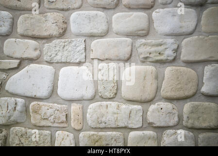 Old stone wall background with rounded limestone cobbles in the wall of a waterfront cottage on georgian bay. Has cement mortar between. Stock Photo