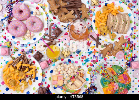 Childrens party food including sandwiches, cake, jelly and ice cream, biscuits, crisps, sweets and doughnuts on a polka dot background. Pattern Stock Photo