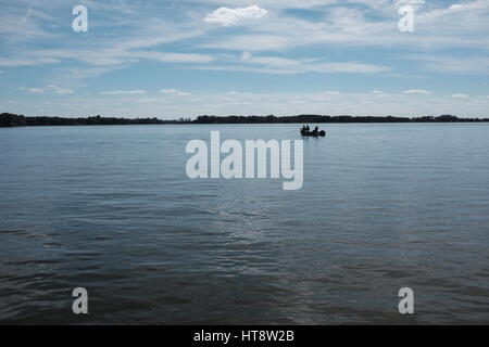 On a gorgeous day, three friends take time off to have fun, relax, and go boating and fishing on the placid waters of Lake Dora in Central Florida. Stock Photo