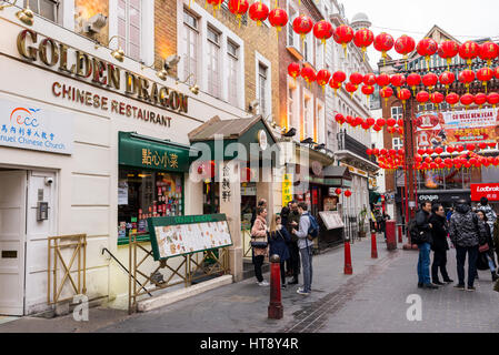Tourists in Gerrard street decorated with Chinese lanterns for the Chinese New Year celebrations. Chinatown, London, UK Stock Photo