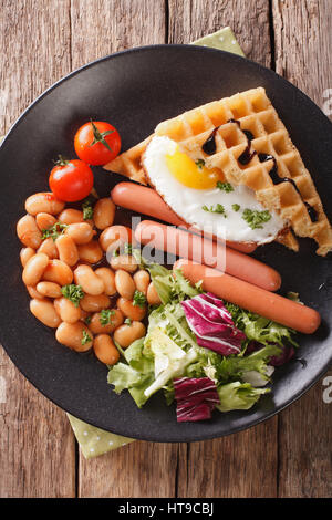 Healthy breakfast: waffle sandwich with egg, sausages, beans and salad close-up on a plate. Vertical view from above Stock Photo