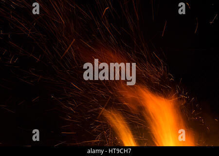 Photo of hot sparking live-coals burning, spark of bonfire. Stock Photo