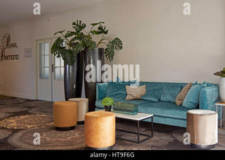 Colorful and stylish seats and sofa with table and green plants in restaurant of hotel. Stock Photo