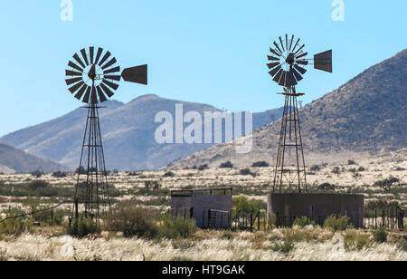 Two windmill water pumps in the heat haze on farm Stock Photo