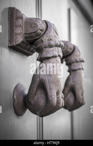 Rusty hand shaped knocker in an old door. Defocused blurry background. Stock Photo