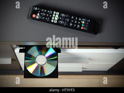 Remote control and Blu-ray or DVD player with inserted disc. Stock Photo